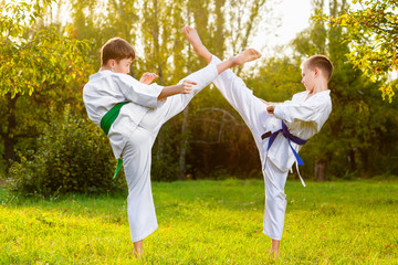 boys in white kimono during training karate exercises at summer outdoors - 98618347