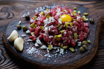 Beef tartar served on a rustic wooden cutting board, close-up