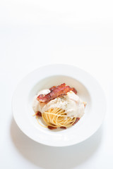 Bacon spaghetti in white plate on wooden background.