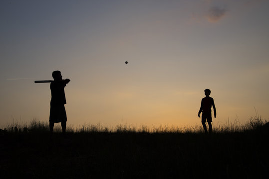 Silhouette of father and son playing baseball outdoors