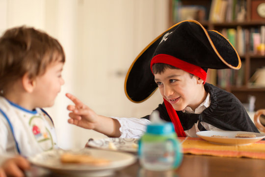 Boy dressed in pirate costume playing with toddler brother