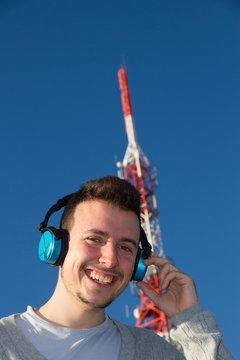 Hombre Joven Alegre con Cascos al lado de una Antena de Telecomunicaciones