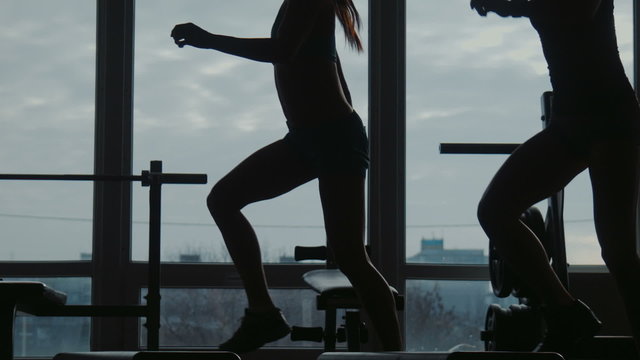 Girl with instructor do fitness exercise together using a step in sport gym
