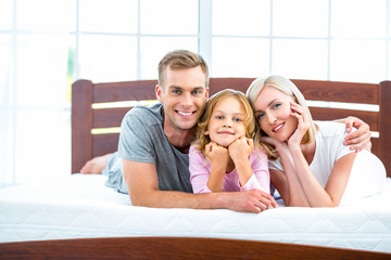 Young family lying on white bed