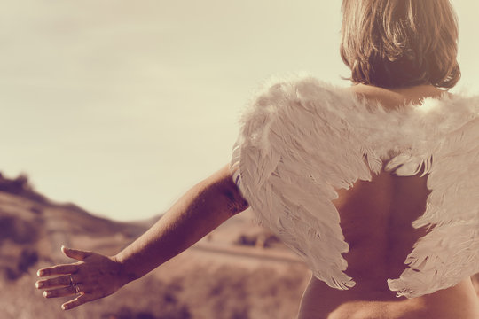 Rear view of a woman wearing a pair of angel wings with outstretched arms