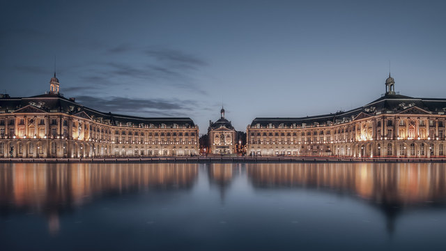 Illuminated neoclassical buildings reflected in the Garonne river, Place de la Bourse, Bordeaux, Gironde, France