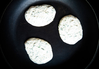Raw pancakes with herbs on a pan. Toned