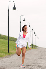 Sporty fitness woman stretching legs before running