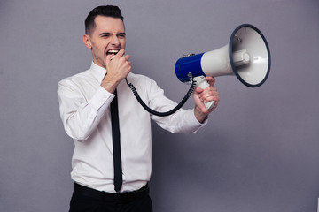 Young businessman screaming in megaphone