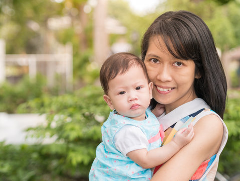 Beauty Asian mother carry cute baby in garden outdoor.