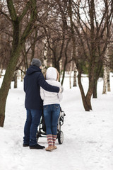 Fototapeta na wymiar Happy young family walking in the park in winter