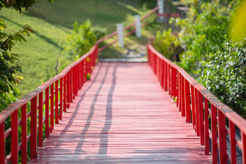 Obraz premium Red wooden bridge over the river in the park.