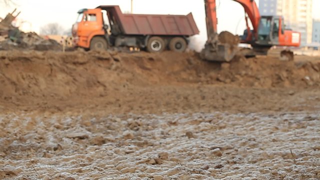 Excavator pours sand into the back of truck