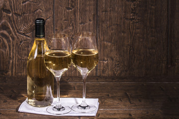 Bottle and a two glass of white wine are standing on the napkin
