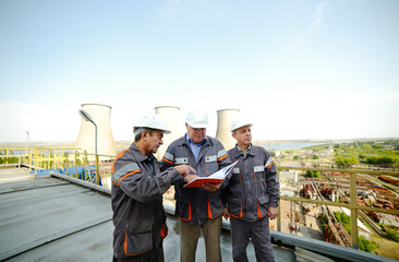Three workers in helmets discussing project