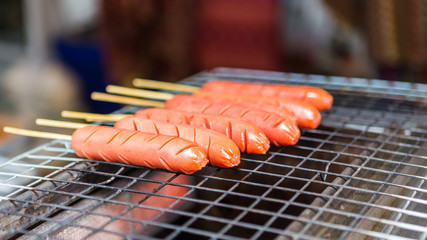 Sausage grilles on fire in street market