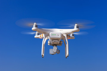 White drone with hovering with blue sky in the background