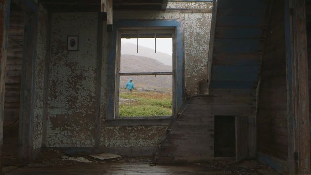 Expeditioner walks by an abandoned house in Hebron, Newfoundland and Labrador on a snowy day. Slow Motion