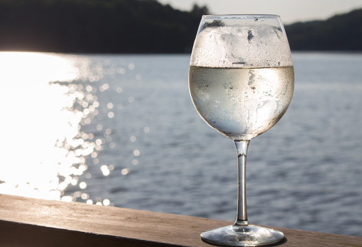 White wine spritzer on the wooden deck of a Canadian cottage summer sunset landscape