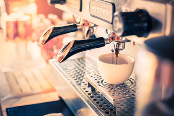 Professional coffee machine with white cup and pouring drink