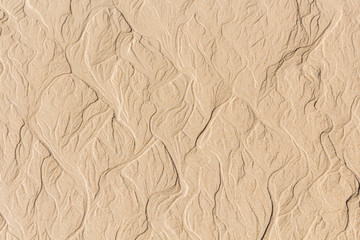 Beach sand erosion pattern. Water formed meanders on beach.
