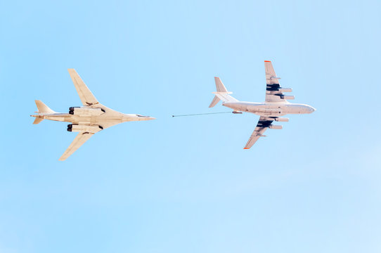 Ilyushin Il-78 (Midas) four-engined aerial refueling tanker and Tupolev Tu-160 (Blackjack) supersonic variable-sweep wing heavy strategic bomber demonstrate refueling against blue sky background.
