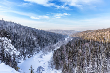 Aerial view of snow-covered trees in the mountains. Valley of the frozen river