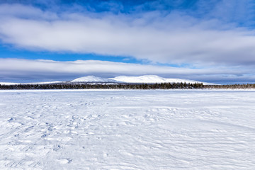 Fototapeta na wymiar Panorama swamp covered with snow on winter mountain background