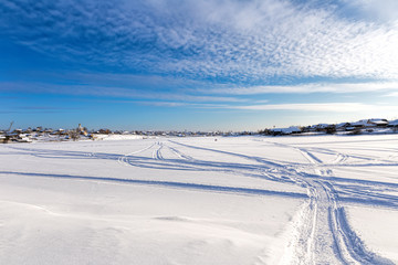 Fototapeta na wymiar Traces of the snowmobile on the frozen lake