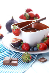Chocolate fondue with fresh berries on a blue wooden table