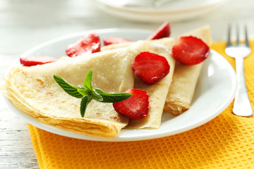 Tasty pancakes with strawberry on white wooden background