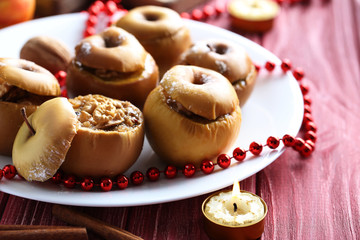 Baked apples on plate on red wooden table
