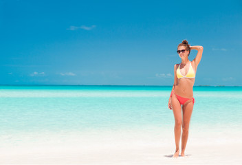 young girl in bright bikini walking at tropical beach