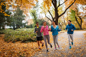 Naklejka premium Young friends jogging at the park.Autumn season.