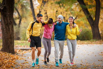 A lively group of young friends enjoys a refreshing jog in the park during the vibrant autumn...