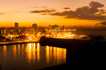 Sunset in Havana with a view of  the city skyline and an old spanish cannon