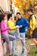 The group of friends, invigorated from their jog, find a spot in the park to relax, sharing laughter and stories as they enjoy the pleasant autumn day.