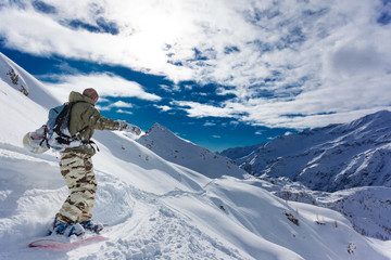 Fototapeta na wymiar Snowboarder goes downhill over a snowy mountain landscape.
