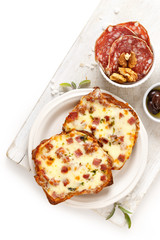 Grilled sandwiches with cheese and chopped salami on the white table