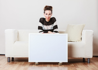 woman on sofa holding blank presentation board.