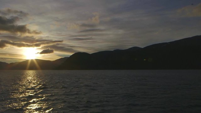 Sun beginning to set behind mountains. Slow Motion