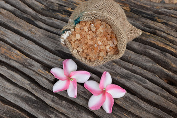 Sugar and Plumeria flower on hemp sackcloth with the old wood background.Selective focus with shallow depth of field.
