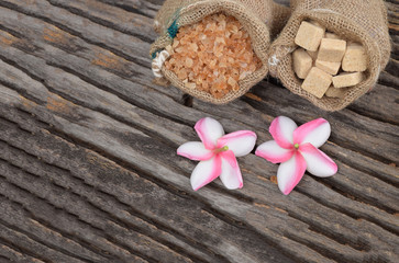 Sugar and Plumeria flower on hemp sackcloth with the old wood background.Selective focus with shallow depth of field.
