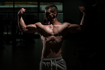 Fototapeta na wymiar Biceps Pose In A Dark Room