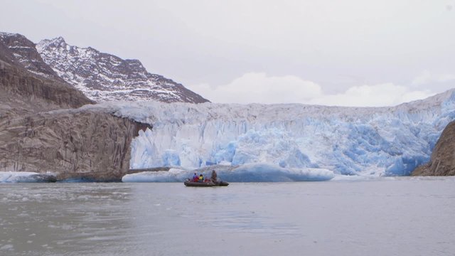 Tourists on a zodiac boat tour in Greenland during an expedition near a glacier. Slow Motion