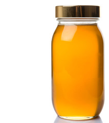 Pure honey in a tall glass jar over white background