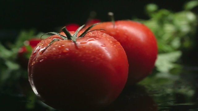 Close-up of ripe tomato rolling over the table; lettuce on the background