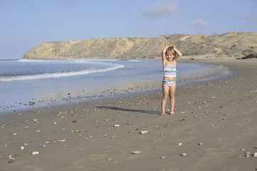 A little girl is playing on the beach.