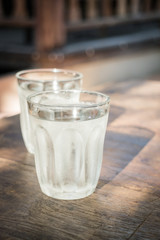 Double glasses of cold water on wooden table