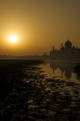 The beautiful view of Taj Mahal with reflection during sunrise from the Yamuna river Agra, India.